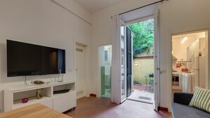 A modern living room with a flat-screen TV, wooden dining table, and a sofa. - Mamo Florence - Maruffi Apartment (Florence)