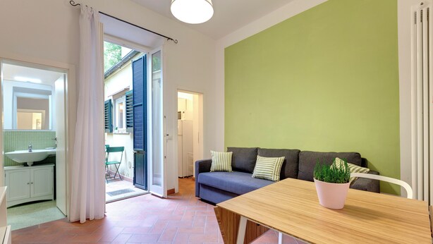 A modern living room with a wooden table, a sofa with cushions, and a potted plant. - Mamo Florence - Maruffi Apartment (Florence)