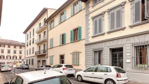 A row of parked cars along a street with buildings featuring balconies and shutters. - Mamo Florence - Maruffi Apartment (Florence)