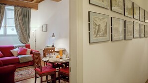 A cozy living room with a red sofa, wooden dining table, and framed artwork on the wall. - Mamo Florence - Palazzo Spinelli Apartment (Florence)