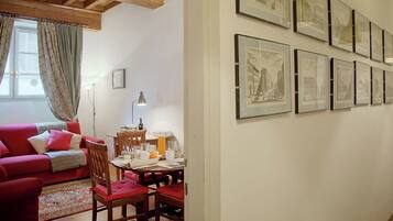 Una sala de estar acogedora con un sofá rojo, una mesa de comedor de madera y cuadros en la pared.