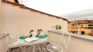 A balcony with a round table and white metal chairs, a book, a cup, and a kettle. - Mamo Florence - Parione Apartment (Florence)