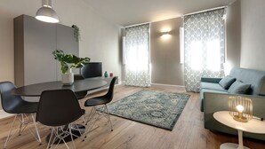 Un soggiorno moderno con zona pranzo, un divano, un tavolino e una televisione.