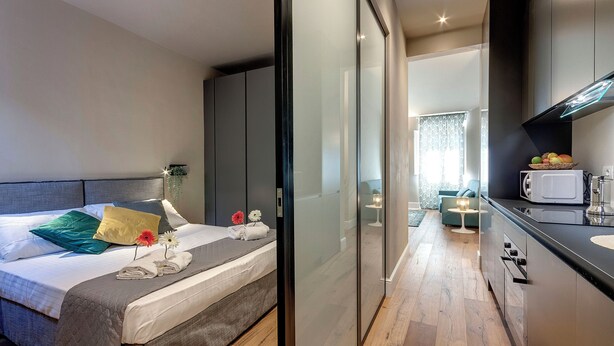Una camera d'albergo moderna con un letto, un comodino e vista sull'area della cucina.