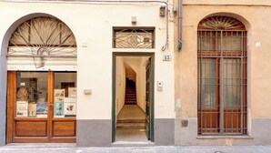 Un edificio con una porta in legno, una scala e una finestra con inferriate.