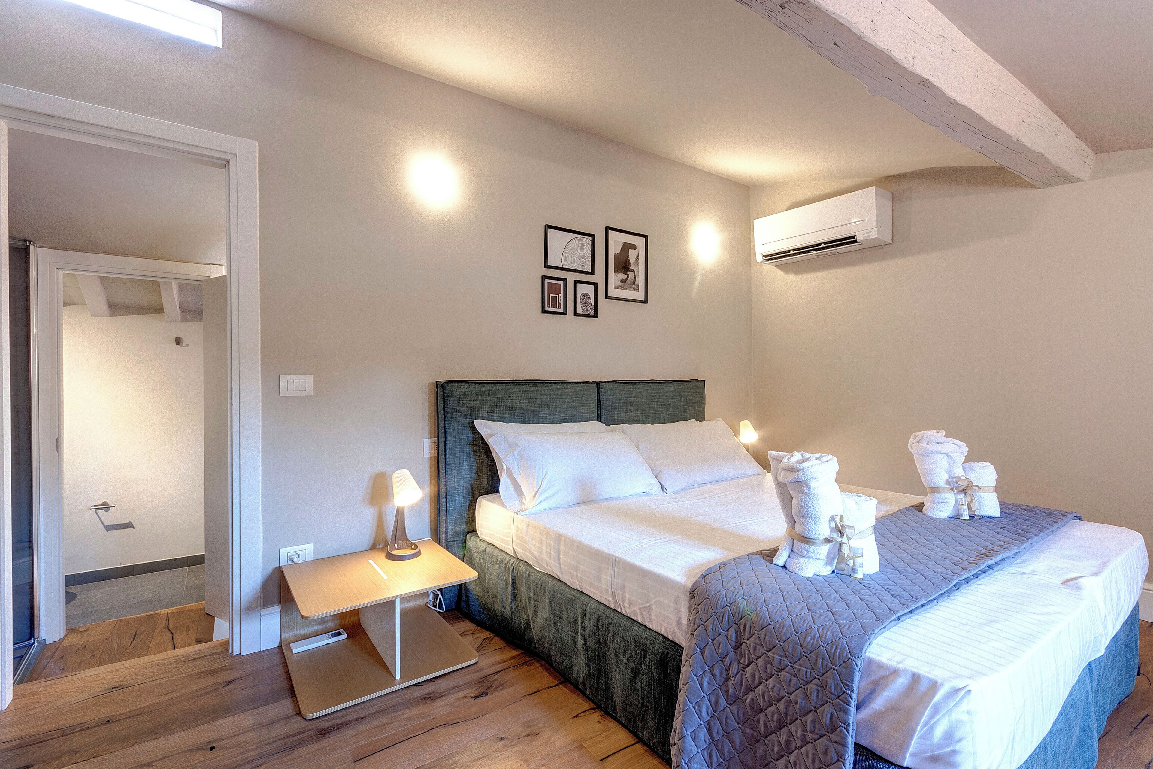 Een slaapkamer met een bed, nachtkastje en een wandairconditioning.