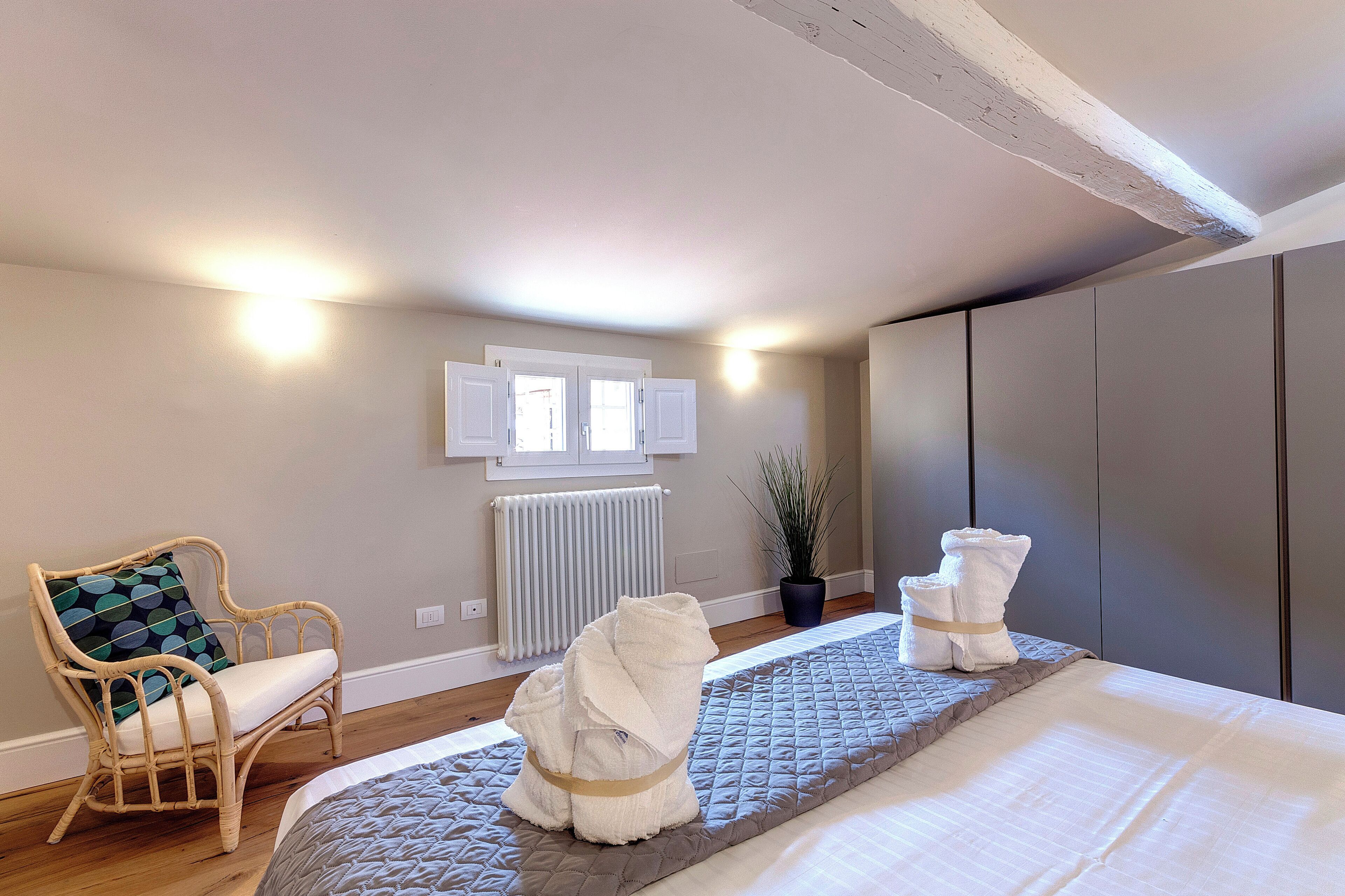 Une chambre d’hôtel avec un lit, une chaise, un radiateur et une plante en pot.