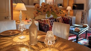 Un coin repas avec une table dressée pour quatre personnes, agrémenté d’un vase de fleurs, d’une bougie et d’un photophore en verre.