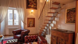 Un salon avec un escalier, des canapés en cuir, un radiateur et un tableau.