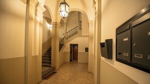 Un couloir avec un escalier, un luminaire et des armoires à dossiers.