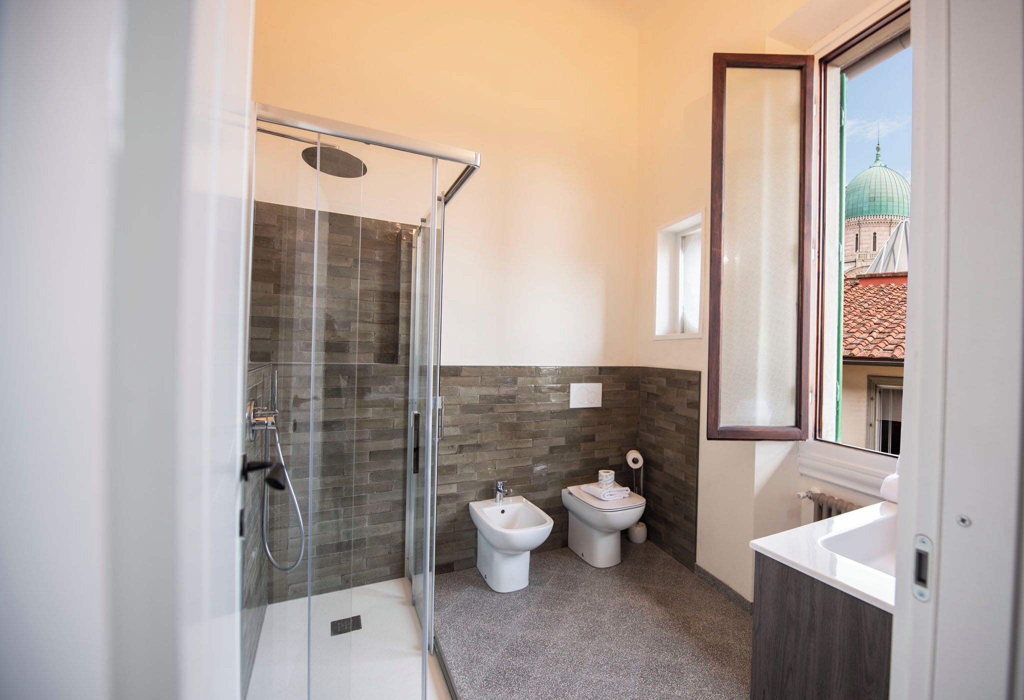 A modern bathroom with a glass-enclosed shower, a bidet, a toilet, and a sink.