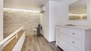 Ein modernes Badezimmer mit einer Steinwand, einem weißen Waschtisch mit Schubladen und einem Spiegel.