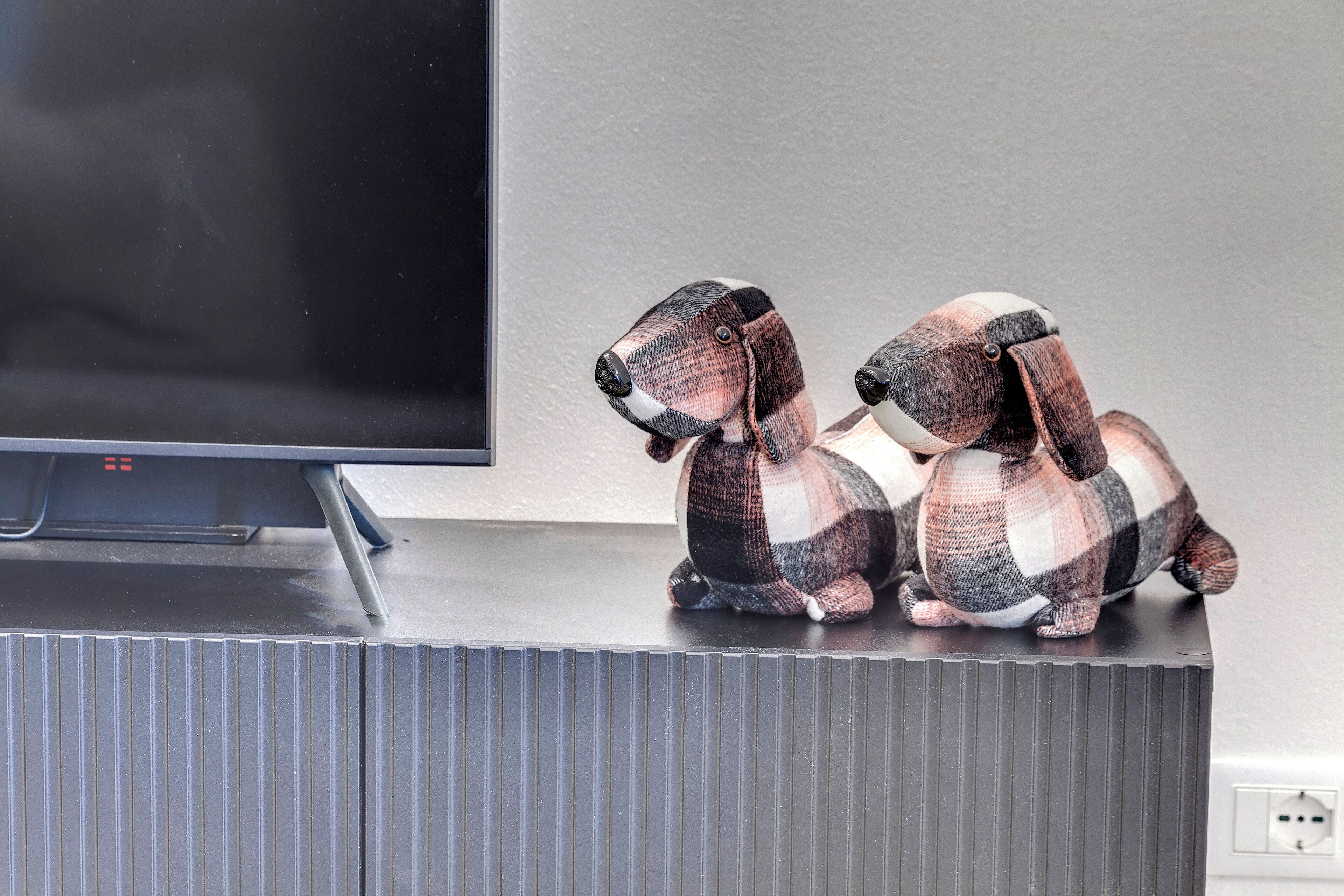 A television on a stand with two plush dog figurines on top.