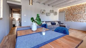 Un soggiorno moderno con zona pranzo, caratterizzato da una parete in mattoni, un divano e un tavolo da pranzo in legno.