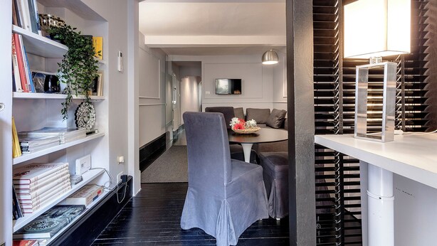 Un salon moderne comprenant un coin repas, une bibliothèque et un téléviseur.