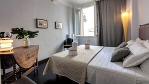 Une chambre d’hôtel avec un lit, des tables de chevet, une plante en pot et une fenêtre avec des rideaux.
