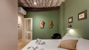 Une chambre d’hôtel avec un lit, des serviettes, une chaise et des œuvres d’art accrochées au mur.