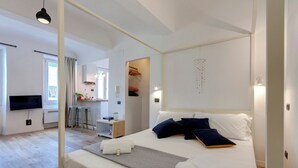 Et moderne hotelværelse med en stor seng, fjernsyn, skrivebord og tekøkken.