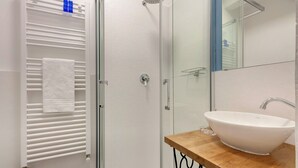 Ein modernes Badezimmer mit Duschkabine aus Glas, einer weißen Badewanne und einem hölzernen Waschtisch.
