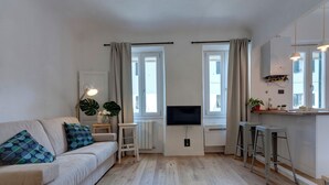 Ein modernes Wohnzimmer mit Sofa, Fernseher und Bar.