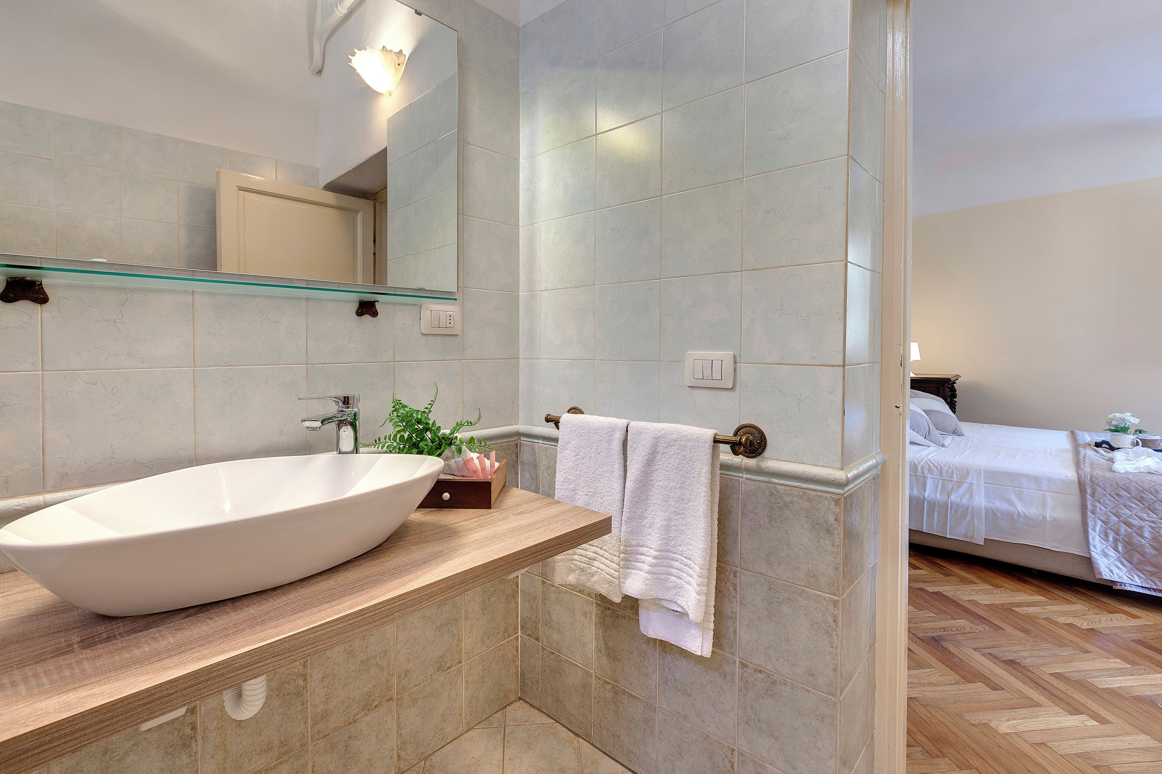 A bathroom with a large vessel sink, a mirror, and a towel rack.