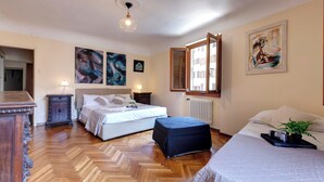 Un dormitorio con cama, mesitas de noche, cómoda, ventana y obras de arte en las paredes.