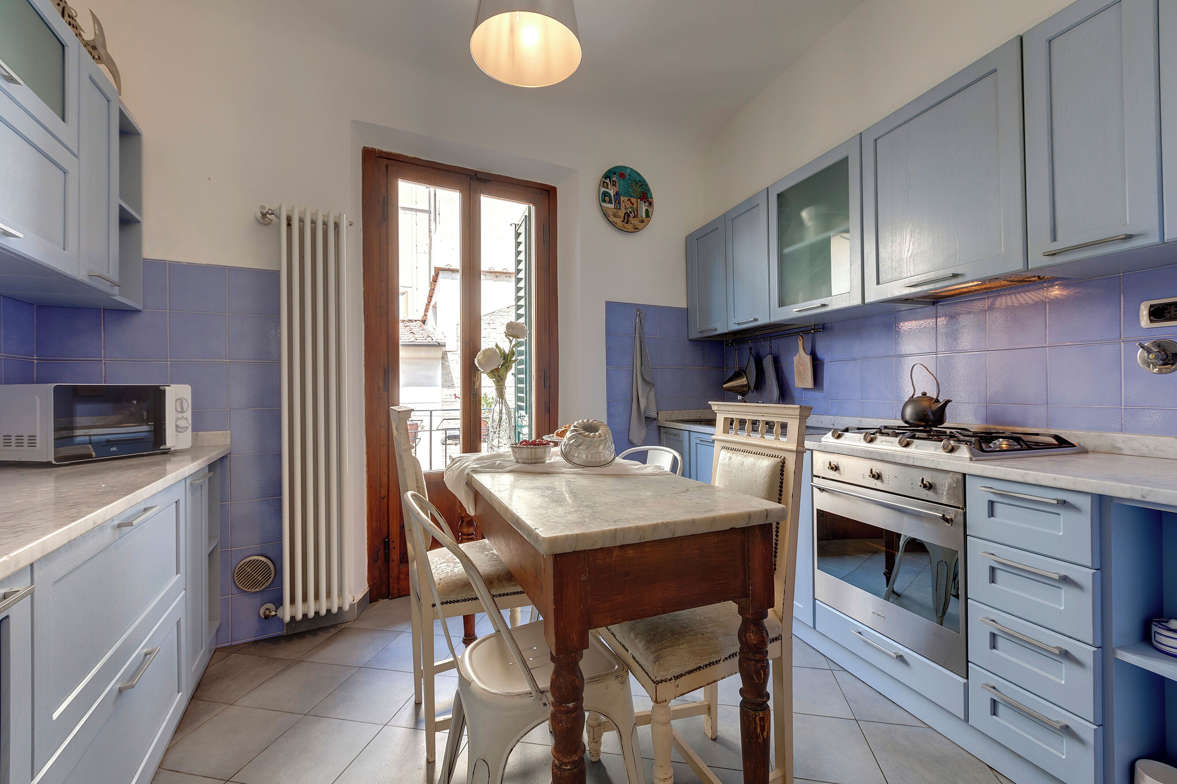 Una cucina con mobili blu, un tavolo di legno e un fornello.