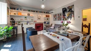 Una sala de estar moderna con comedor, que incluye una estantería, una chimenea y un cuadro abstracto de gran tamaño.
