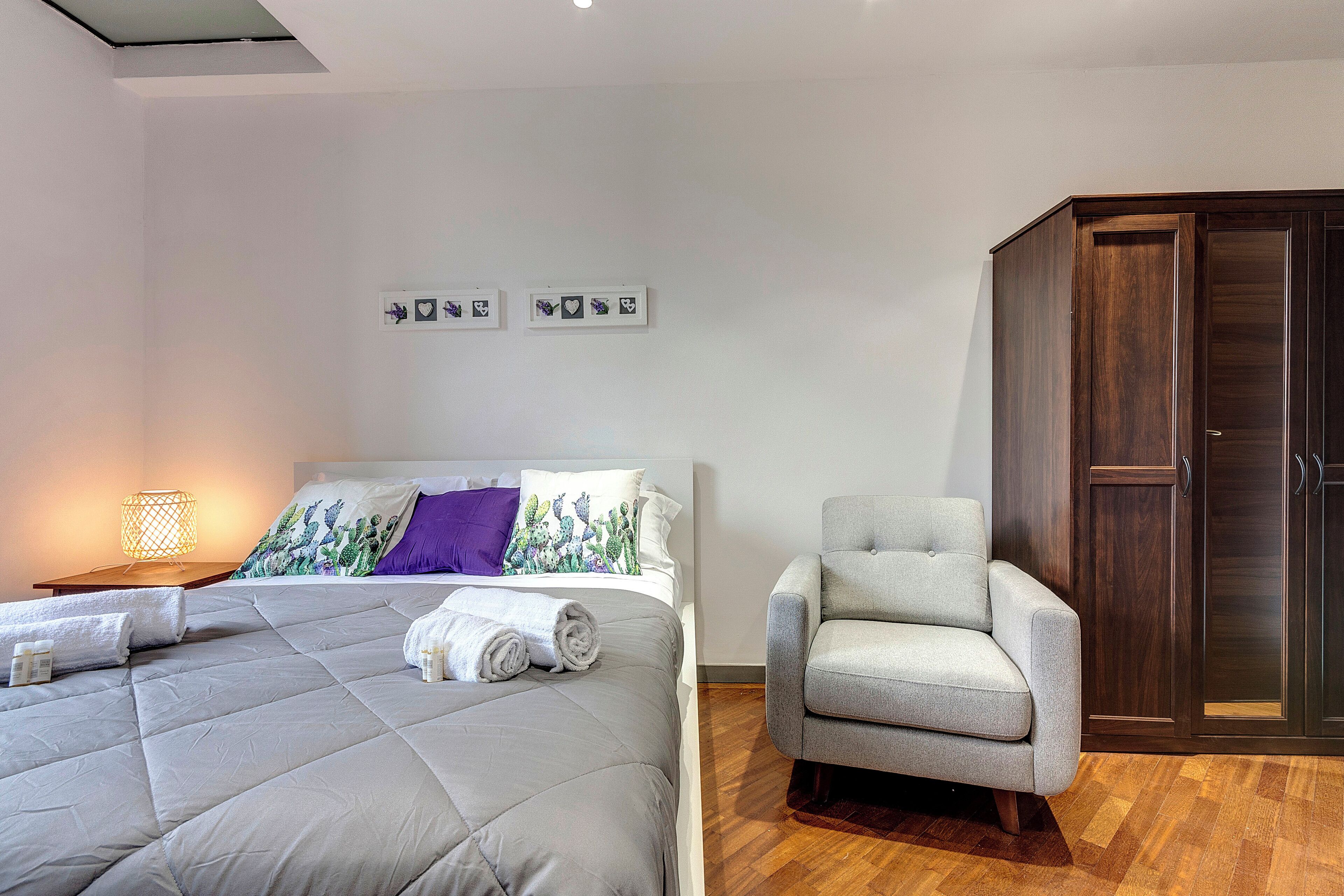 Ein Schlafzimmer mit Bett, Stuhl, Kleiderschrank und Wandbildern.