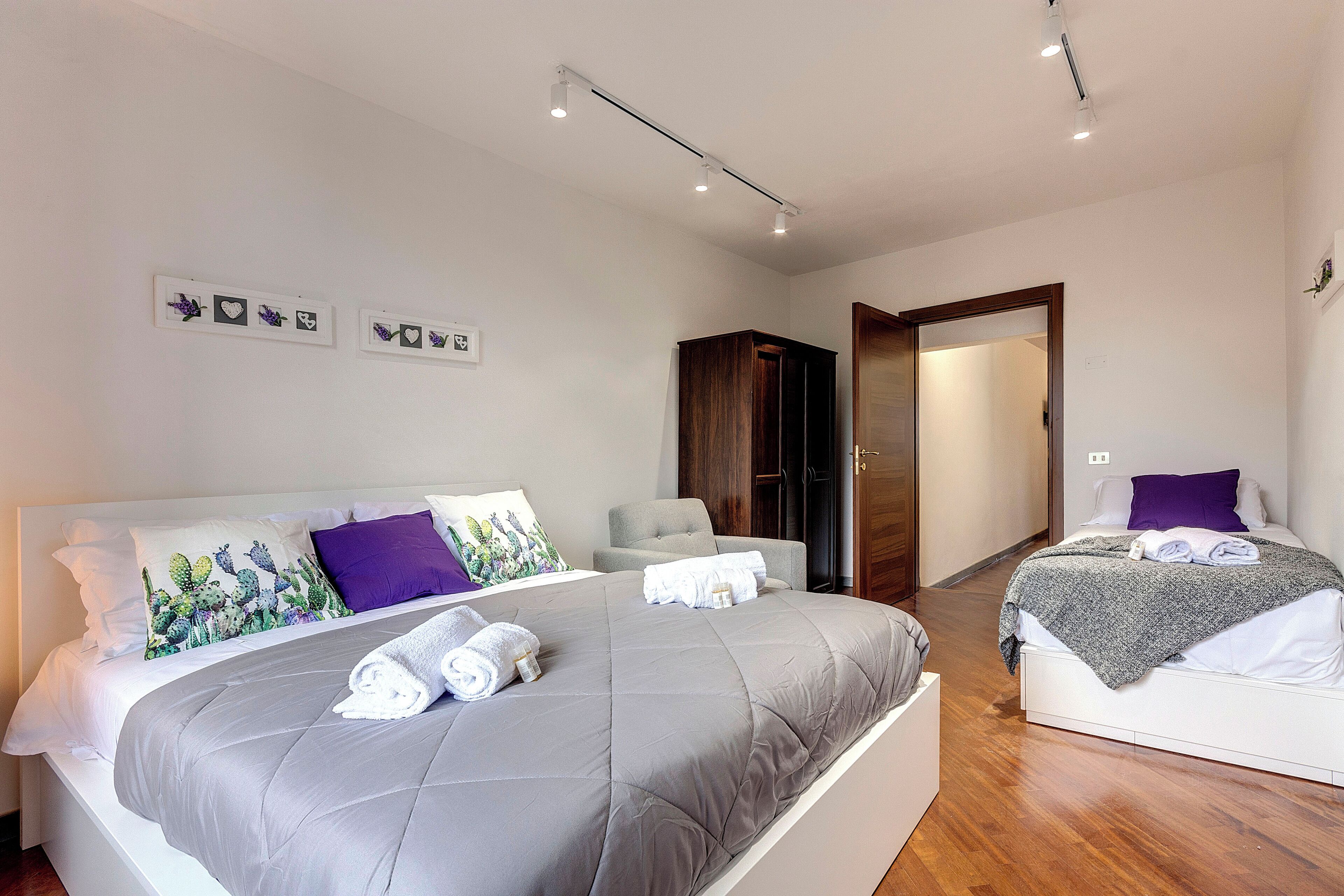 A modern bedroom with a large bed, a smaller bed, and a seating area.