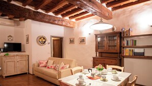 Una sala de estar acogedora con techo de madera, un sofá, una mesa de comedor lista para el té y una estantería.