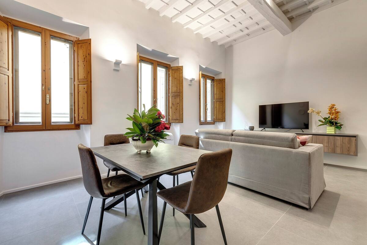 Una sala de estar moderna con comedor, que incluye un sofá, televisión y una mesa de comedor con sillas.