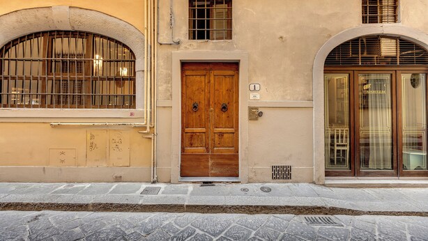A building with a wooden door, a window with bars, and an arched entrance. - Mamo Florence - Venere & Zefiro Apartments (Florence)