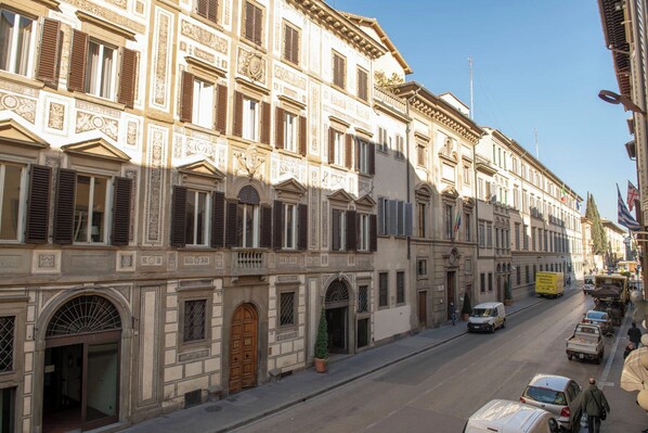 A street view with historic buildings, a clear sky, and parked vehicles.