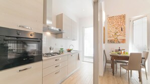 Una cocina moderna con horno empotrado, cocina a gas y comedor con mesa y sillas.