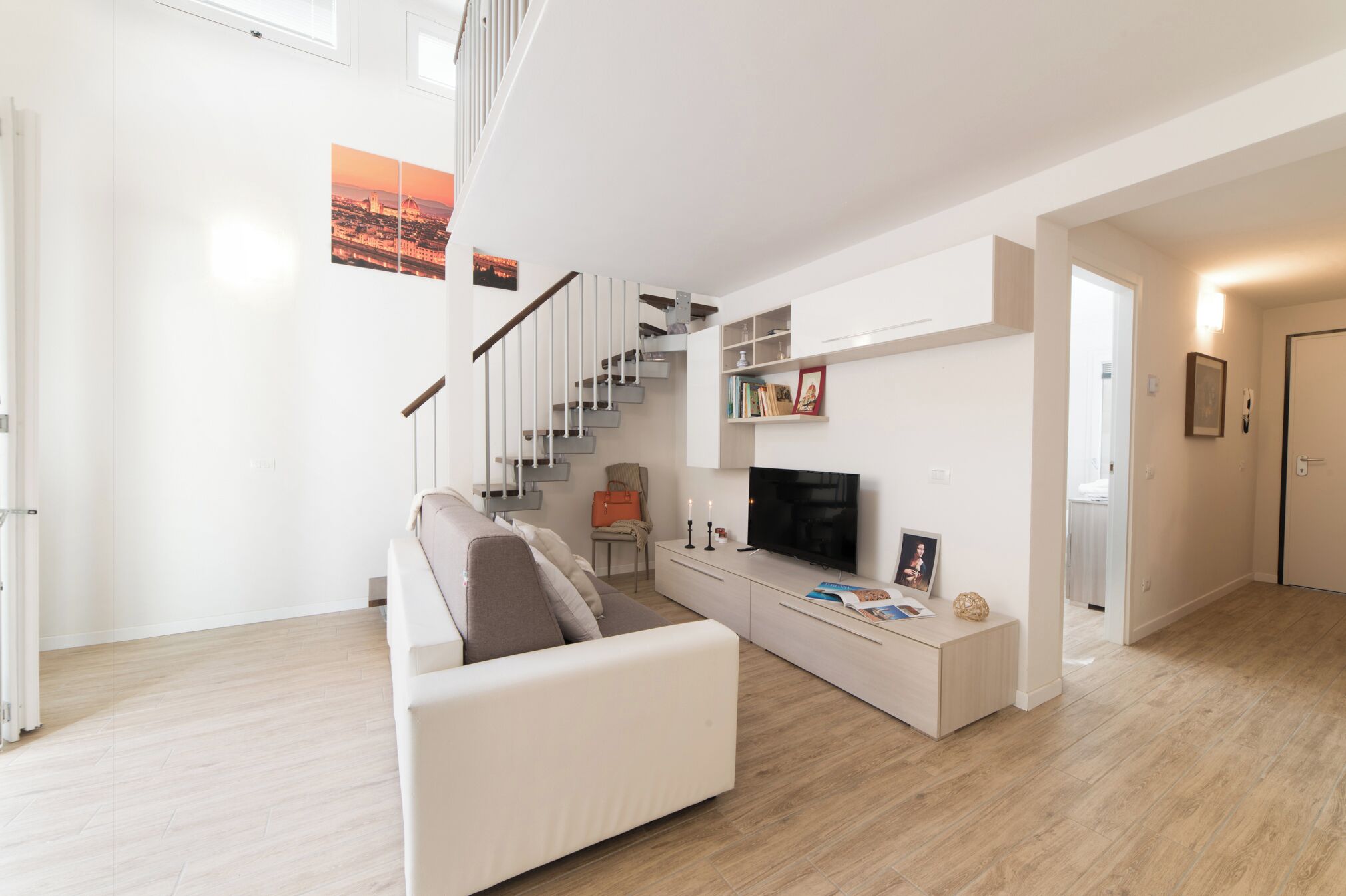Ein modernes Wohnzimmer mit einem weißen Sofa, einem Flachbildfernseher und einer Treppe.
