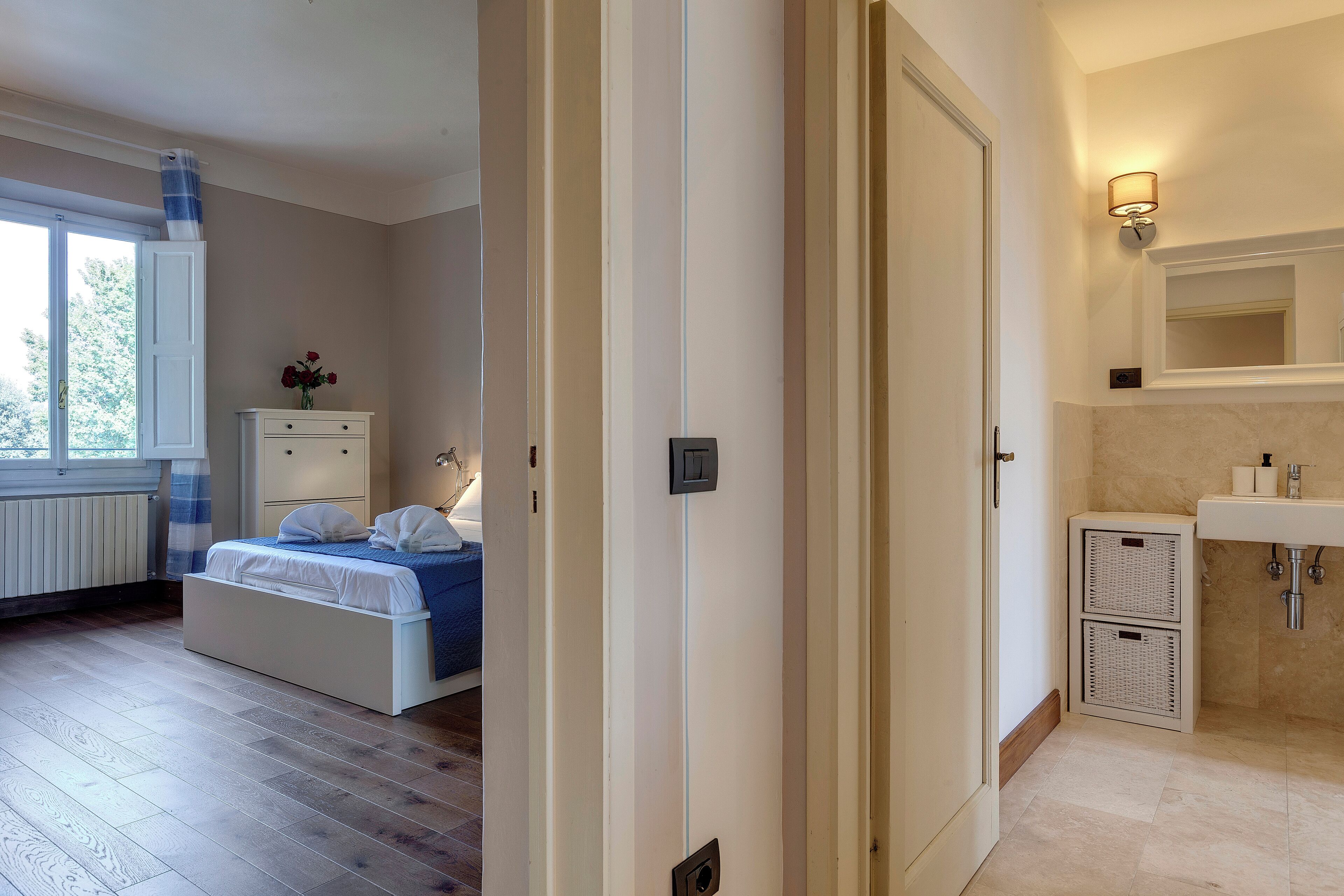 Quarto com cama, penteadeira, mesa de cabeceira e janela.