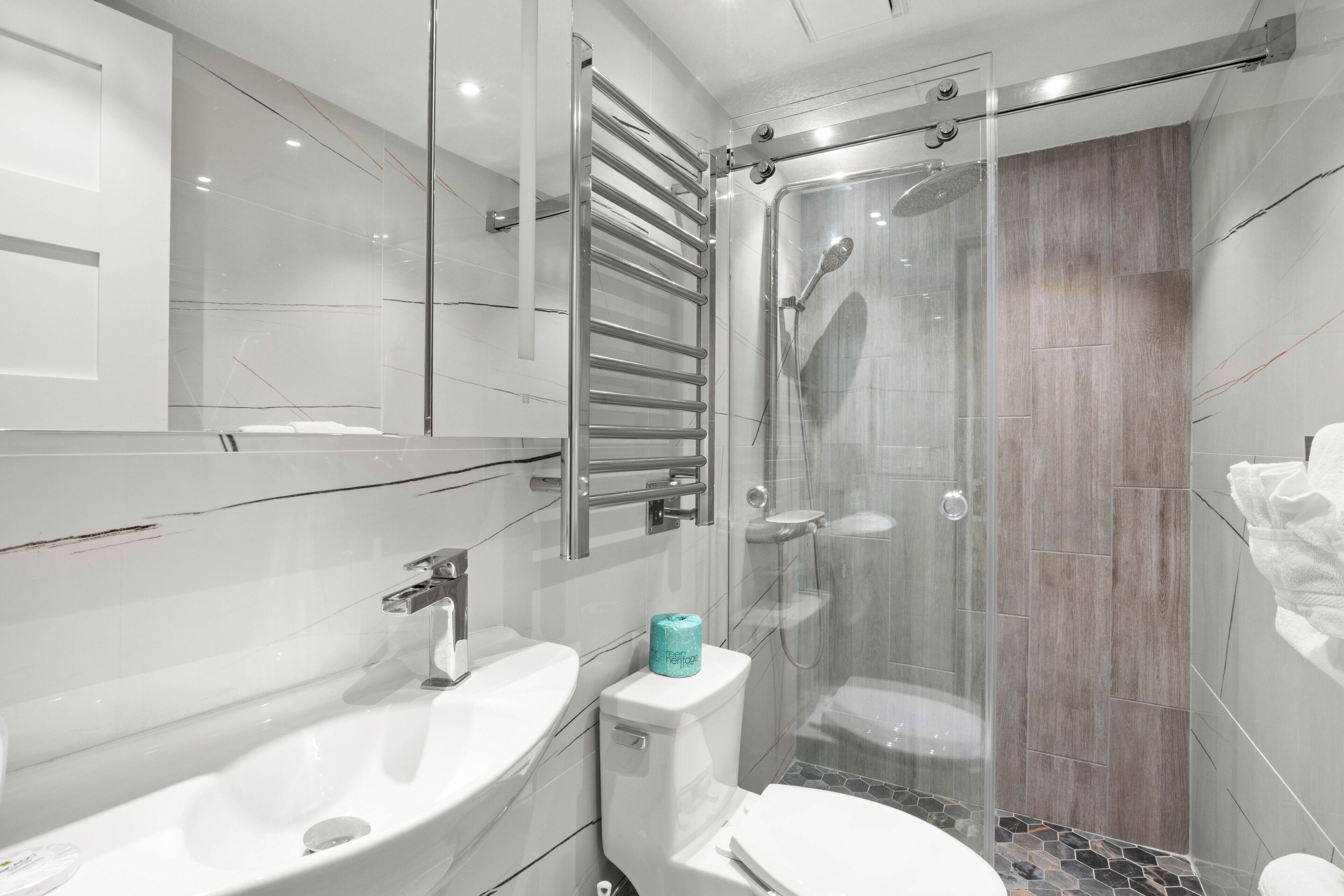 A modern bathroom with a glass-enclosed shower, a white sink, and a toilet.
