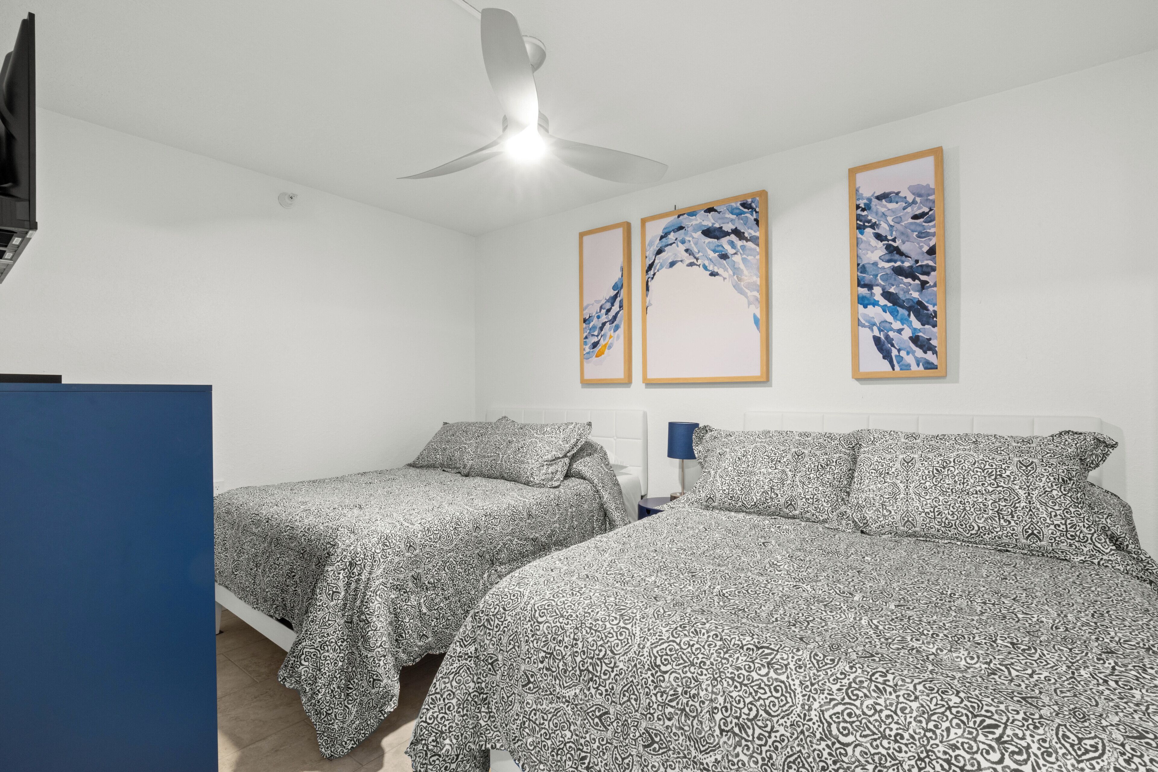 Een kamer met twee bedden, een plafondventilator en lijstwerken aan de muur.