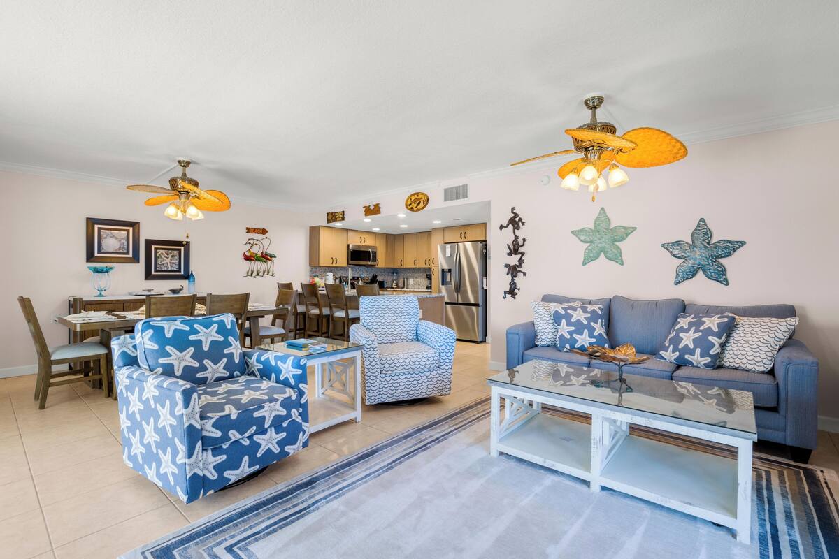 Un salon comprenant un canapé, un fauteuil, une table basse et un ventilateur de plafond.