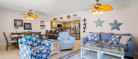 Un salon comprenant un canapé, un fauteuil, une table basse et un ventilateur de plafond.