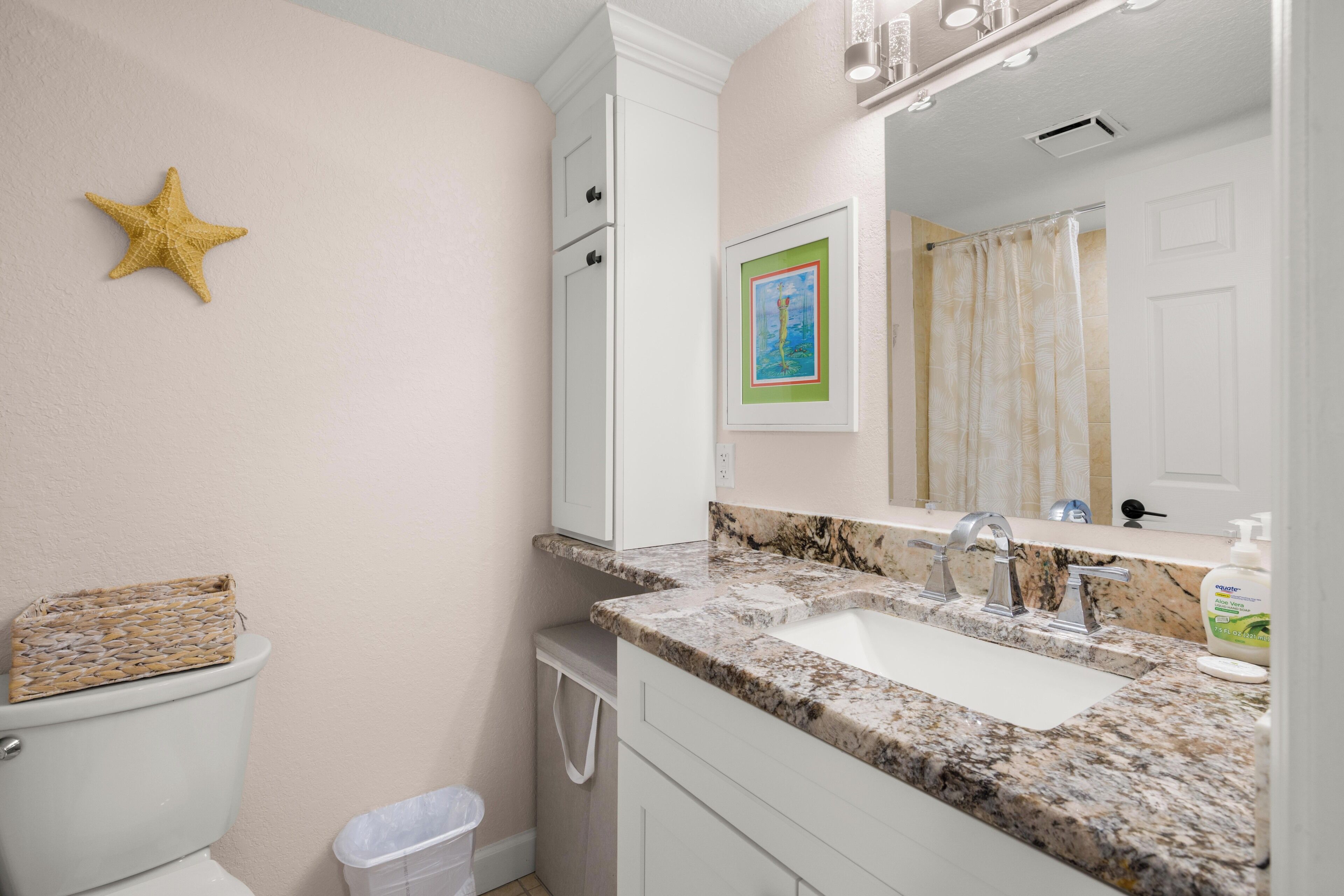 A bathroom with a toilet, a sink, a mirror, and a star decoration on the wall.