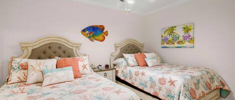 A bedroom with two beds, a ceiling fan, and a wall painting.
