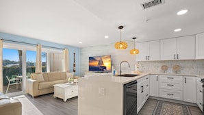 A modern kitchen with white cabinetry, a central island, and pendant lighting. - Fifty Gulfside Condominiums (Indian Rocks Beach)