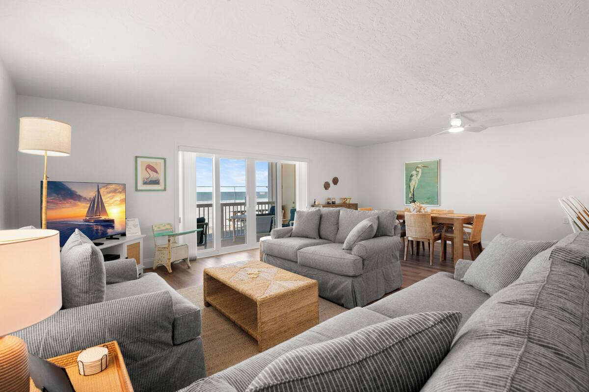 Un salon avec un canapé, une table basse et un téléviseur. Il y a un balcon avec vue.