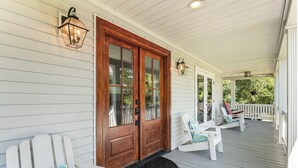 A porch with a wooden door, white chairs, and a bench. - Private 4-Bedroom Lakeside Estate Sleeps 10 with Pool, Fire-pit, Wi-Fi, AC (Hollywood)