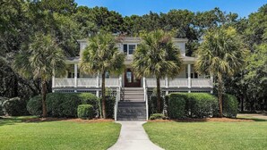 A two-story house with a front porch, palm trees, and a well-maintained lawn. - Private 4-Bedroom Lakeside Estate Sleeps 10 with Pool, Fire-pit, Wi-Fi, AC (Hollywood)