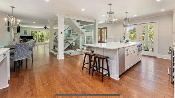 A spacious kitchen with a large island, wooden flooring, and a staircase leading to an upper level. - Private 4-Bedroom Lakeside Estate Sleeps 10 with Pool, Fire-pit, Wi-Fi, AC (Hollywood)