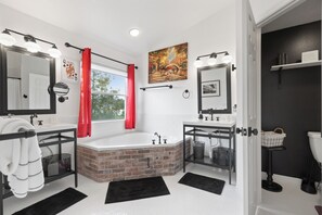 A modern bathroom with a large bathtub, two sinks, and a vanity.