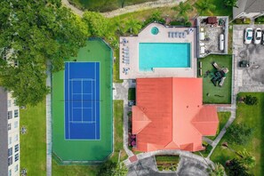 Ilmakuva kiinteistöstä, jossa on tenniskenttä, uima-allas ja punaisella katolla varustettu rakennus.